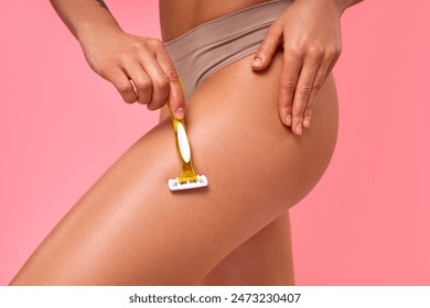 Close-up of a woman shaving her smooth, moisturized leg with a razor on a pink background. Beauty and hygiene concept. High-quality stock image for grooming, skincare, and personal care content. - Powered by Shutterstock