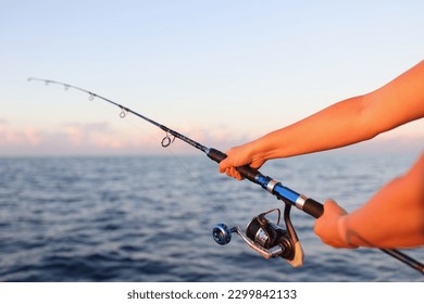 Close-up of woman sitting holding fish rod in hands. Female taking fish in sea or river. Fish and fishery concept - Powered by Shutterstock