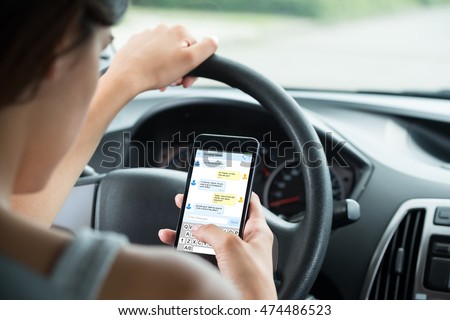 Close-up Of Woman Sitting Inside Car Typing Text Message On Mobile Phone