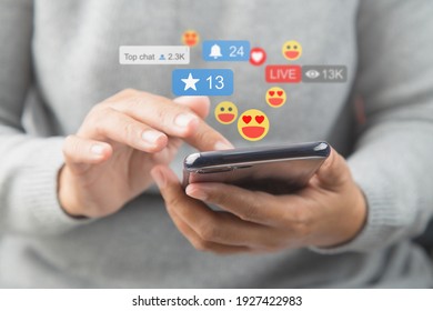 Close-up de uma mulher de camisa macia usando o smartphone, mãos segurando e digitando para se comunicar com outras pessoas por meio de emoji e texto online.