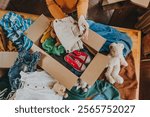 Close-up of woman sorting an old out-of-use kid toy, clothes and shoes in box for charity or converting discarded materials. Upcycling concept.