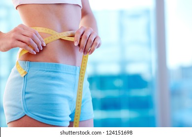 Close-up of a woman in sportswear measuring her waist - Shutterstock ID 124151698