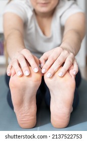 Closeup Of Woman Stretching Hamstring Muscles Holding Her Feet With Hands