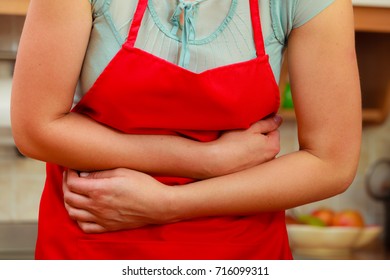 Closeup Of Woman Suffering From Stomach Ache Abdominal Pain. Female In Kitchen.