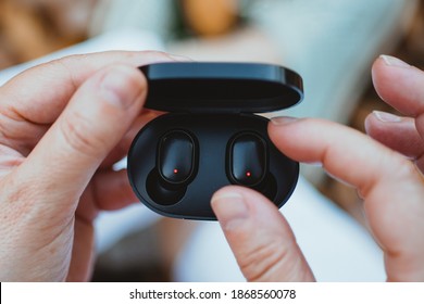 close-up of a woman taking out a wireless earbud from his charging box