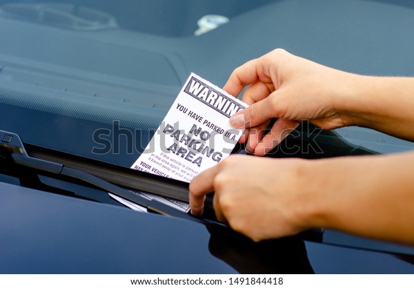Close-up Of A Woman Taking Parking Ticket On\
Car\'s Windshield