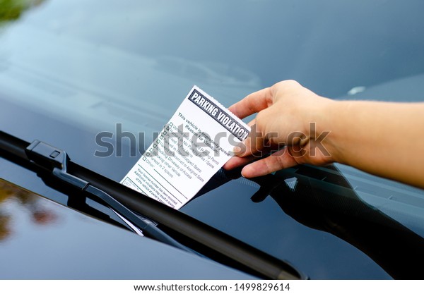 Close-up Of A Woman Taking Parking Ticket On\
Car\'s Windshield