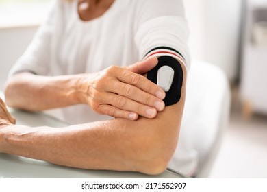 Close-up Of A Woman Testing Glucose Level With A Continuous Glucose Monitor On Her Arm