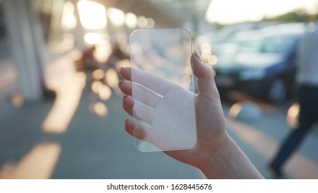 Close-up woman tourist using a mobile phone while wandering through modern busy city center. Smartphone with the latest holographic innovation technology. City life concept. - Powered by Shutterstock