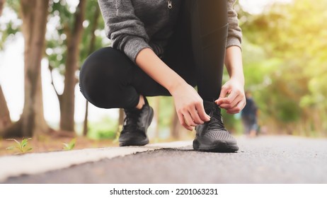 Closeup Of Woman Tying Shoe Laces. Asian Female Sport Fitness Runner Getting Ready For Jogging Outdoors In Public Park