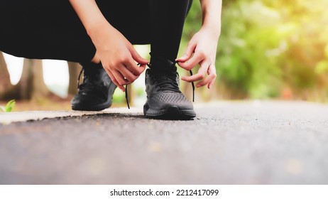 Closeup Of Woman Tying Shoe Laces. Asian Female Sport Fitness Runner Getting Ready For Jogging Outdoors In Public Park