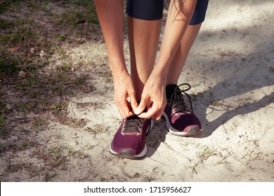 Close-up Of A Woman Tying Shoelaces On Sneakers While Walking Or Doing Exercise Outdoors (in A Park). Activity And Sport Lifestyle Concept. 