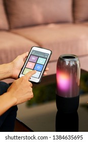 Close-up Of Woman Using Bluetooth On Her Smartphone To Connect The Wireless Speaker, She Wants To Listen To Music At Home