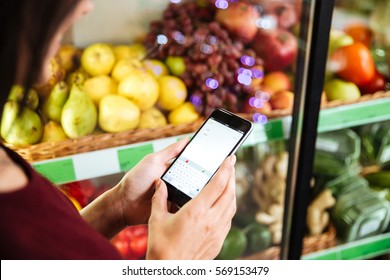 Closeup Of Woman Using Cell Phone In Grocery Store