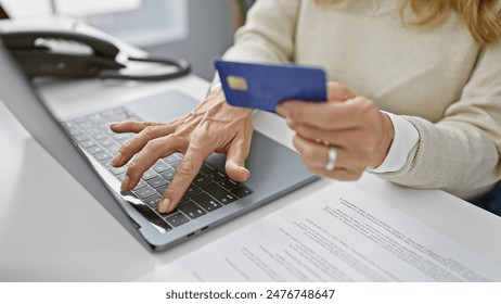 Close-up of a woman using a credit card on a laptop for an online transaction in a modern office - Powered by Shutterstock