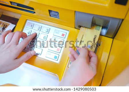 Close-up Of woman Using Credit Card To Withdrawing Money From Atm Machine.