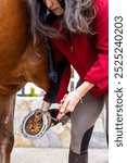 A close-up of a woman using a hoof pick to clean her horse