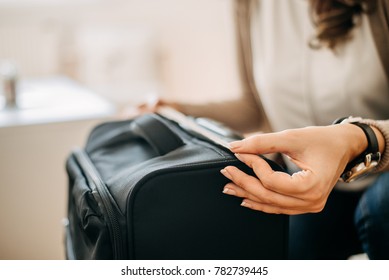 Closeup of woman using measuring tape to measure cabin luggage.