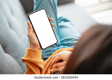 Closeup - Woman Using Mobile Smartphone With Blank White Screen On A Sofa In Living Room, Copy Space.