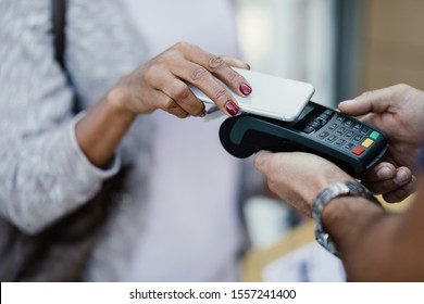 Close-up Of Woman Using Smart Pone While Making Contactless Payment To A Delivery Man. 