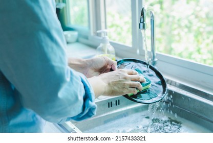 Close-up of a woman washing dishes with dirty food scraps Cleaner in the sink the kitchen counter at home.