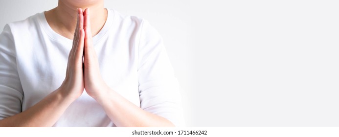 Close-up of woman in white casual is paying respect by using two hand palms splice together; it is a Thai and Asian tradition and culture calling "Wai" for greeting, thanking, apologizing and farewell - Shutterstock ID 1711466242