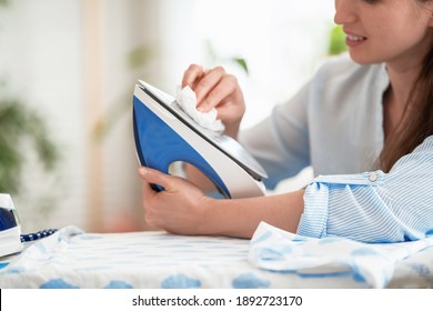 Close-up, woman wipes iron with soft cloth preparing to iron clothes on ironing board after washing at home Modern steam system, new household appliances. Caring for household appliances after work. - Powered by Shutterstock