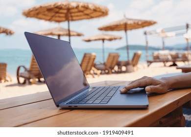 Closeup of a woman working and touching on laptop touchpad on the beach - Powered by Shutterstock