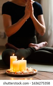 Close-up. Woman In Yoga Lotus Pose Meditating In A Dark Room With Candle Light. Atmosphere Of Relax And Zen. Exercise To Reach Clarity Of Mind And Perfect Body. Wooden Floor, Soft Morning Light