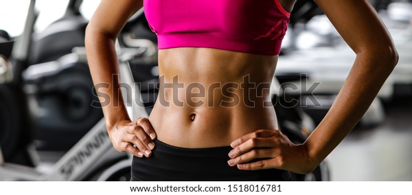 Close-up of a woman's body bodybuilder
in the gym. Portrait of muscular woman showing Strong abs on
professinal gym background. Beautiful abdominal
muscle.