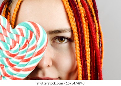 Closeup Of Woman's With Colorful Hair Holding A Heart Lolipop In Front Of Her Face