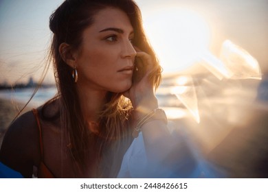 Close-up of woman's contemplative expression with a creative sun glare adding to the mood