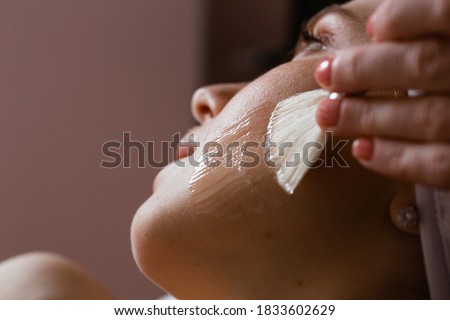 Close-up of a woman's face. The beautician makes a chemical peel. Skin care concept.