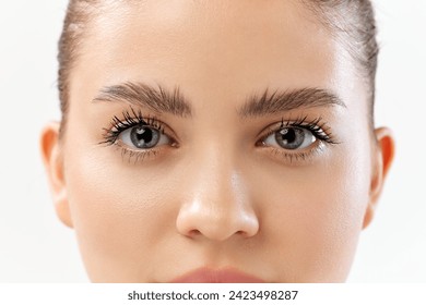 El primer plano de la cara de la mujer se centra en sus ojos, cejas bien definidas y largos latigazos. Productos de maquillaje, laminación y lentes de contacto. Concepto de belleza, cuidado de la piel, cosméticos y cosmetología