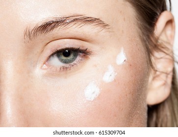 Close-up Of A Woman's Face With Moisturizer On The Cheeks In The Eye Area