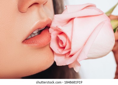 Close-up Of Woman's Face On White Background. The Woman's Lips Have A Pink Rose.