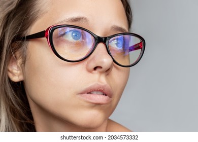 Close-up Of Woman's Face With Red And Black Female Glasses For Working At A Computer With A Blue Filter Lenses Isolated On A Gray Background. Anti Blue Light And Rays. Eye Protection