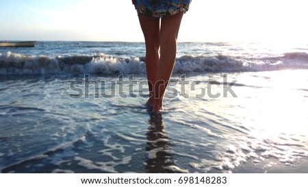 Close-up of woman's feet walking towards the sea. Vacation, traveling and freedom concept.