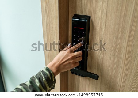 Closeup of a woman's finger entering password code on the smart digital touch screen keypad entry door lock in front of the room. Self Check-in, Modern security,Temporary codes. 