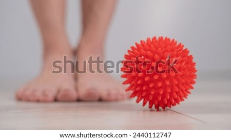 Close-up of a woman's foot on a massage ball with spikes. 