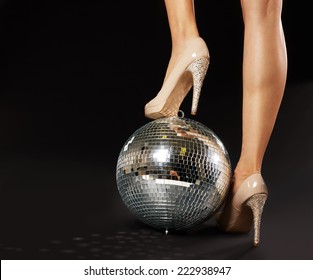 Close-up Of Woman's Foot Wearing Stilettos Over Disco Ball