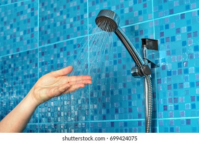 Close-up of a woman's hand check water temperature in the shower with hand shower wall. - Shutterstock ID 699424075