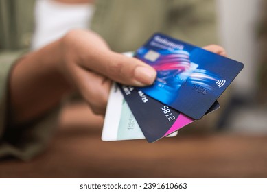 In a close-up, a woman's hand clutches a stack of credit cards, highlighting online payments, shopping, and contactless credit card use. 