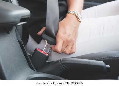 Close-up of a woman's hand fastening a seat belt in a car. Woman driver fastens her seat belt before driving. Driving safety concept.