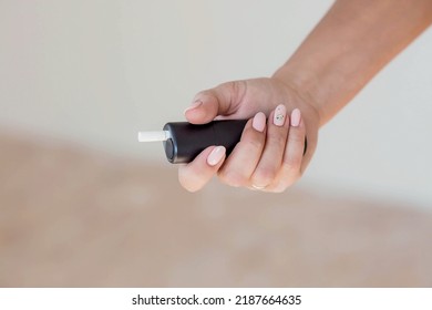 Close-up Of A Woman's Hand. The Girl Is Holding An Electronic Cigarette. Nicotine Addiction. The Concept Of The International Day Of Smoking Cessation.