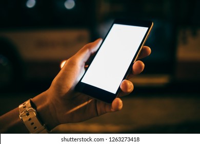 Close-up Woman's Hand Holding Mobile Phone With Blank Touch Screen In City At Night In Yellow Lights.