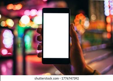 Close-up Woman's Hand Holding Mobile Phone With Empty White Screen In The City At Night.