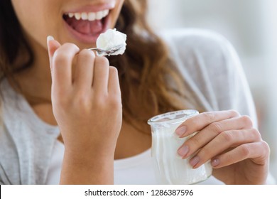 Close-up Of Woman's Hand Holding Yogurt While Eating At Home.