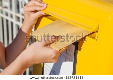 Close-up of woman's hand inserting envelope in mailbox