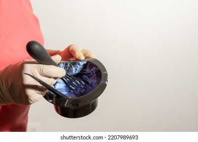 Close-up Of A Woman's Hand With A Latex Glove Making A Mixture Of A Blue Chemical To Dye Hair With A Whisk And A Bowl